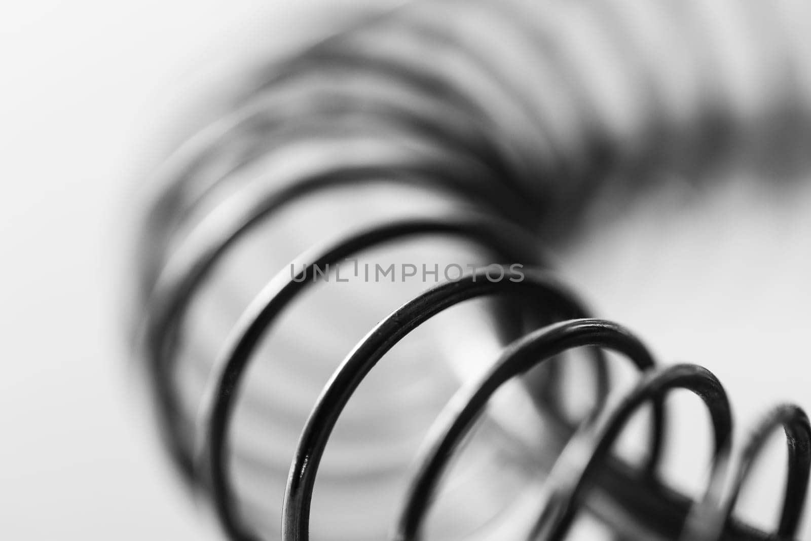 Metal spring coiled, black and white macro shot, soft focus, abstract industrial art