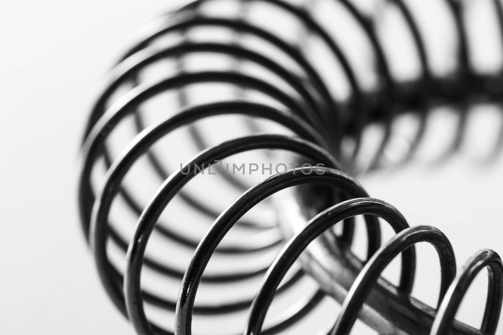 Metal spring coiled, black and white macro shot, soft focus, abstract industrial art