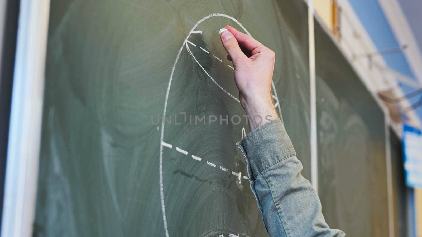 Guy draws figures on the board. Geometry class