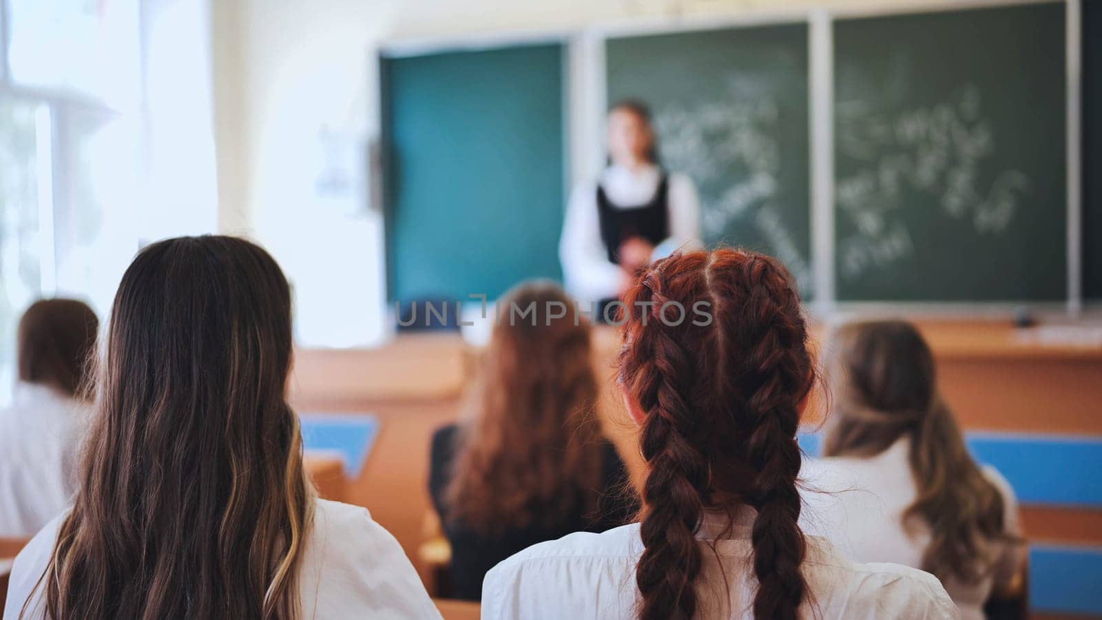 Professor pointing at college student with hand raised in classroom. Student raising a hand with a question for the teacher. Lecturer teaching in class while girl have a question to do during a lesson