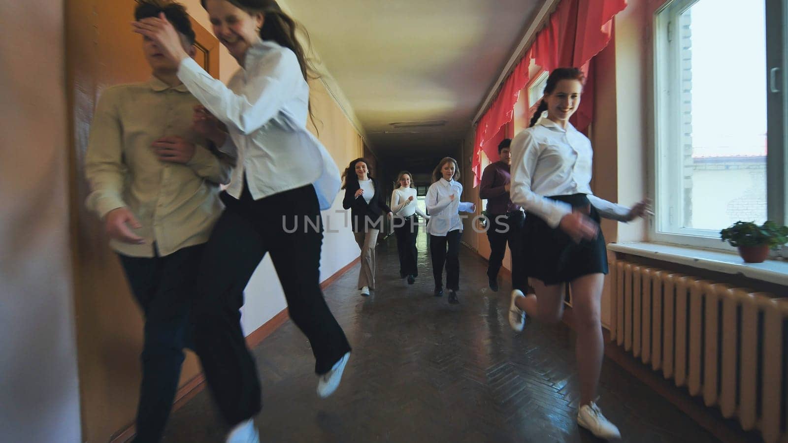 A down-syndrome school boy with group of children in corridor, running.