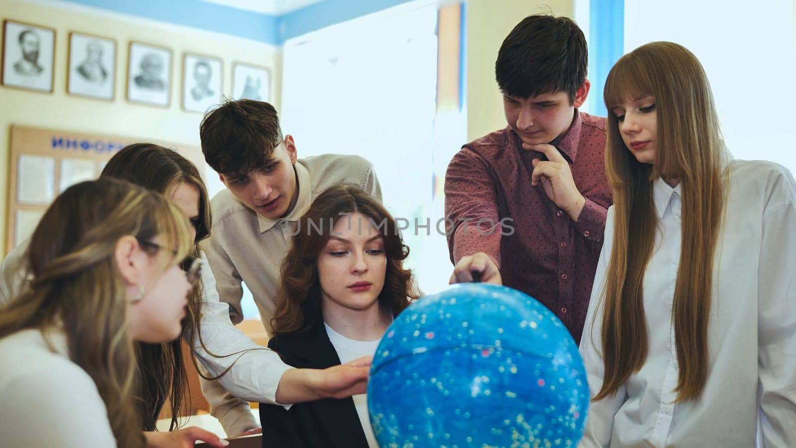 Students look at a globe of the starry sky in a classroom at school. by DovidPro