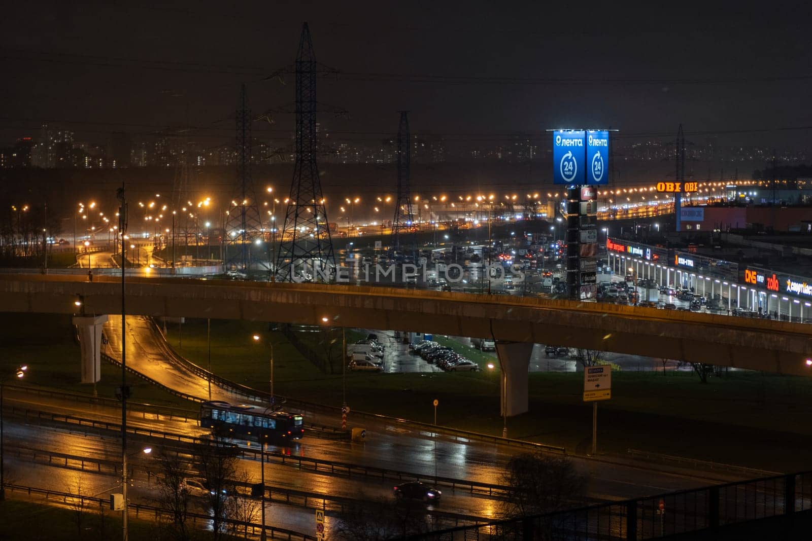 On night roads, cars drive over a bridge and a road junction. Urban cityscape by AnatoliiFoto