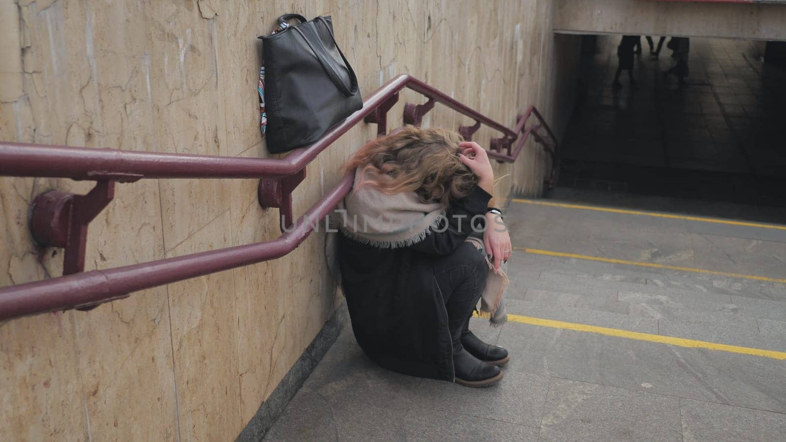 A young girl crying by the stairs in the subway. by DovidPro