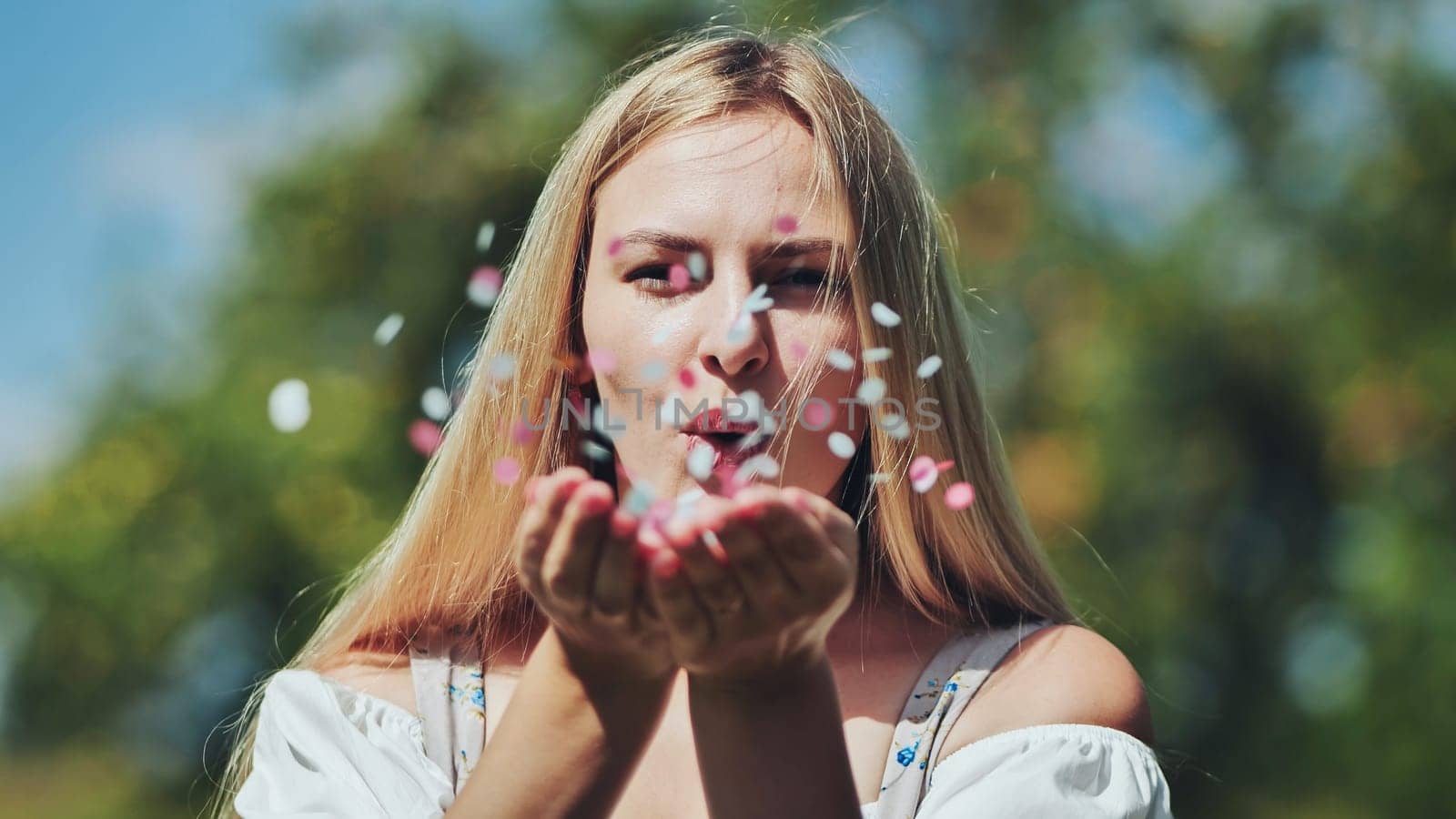 A girl blows a multi-coloured paper confetti out of her hands