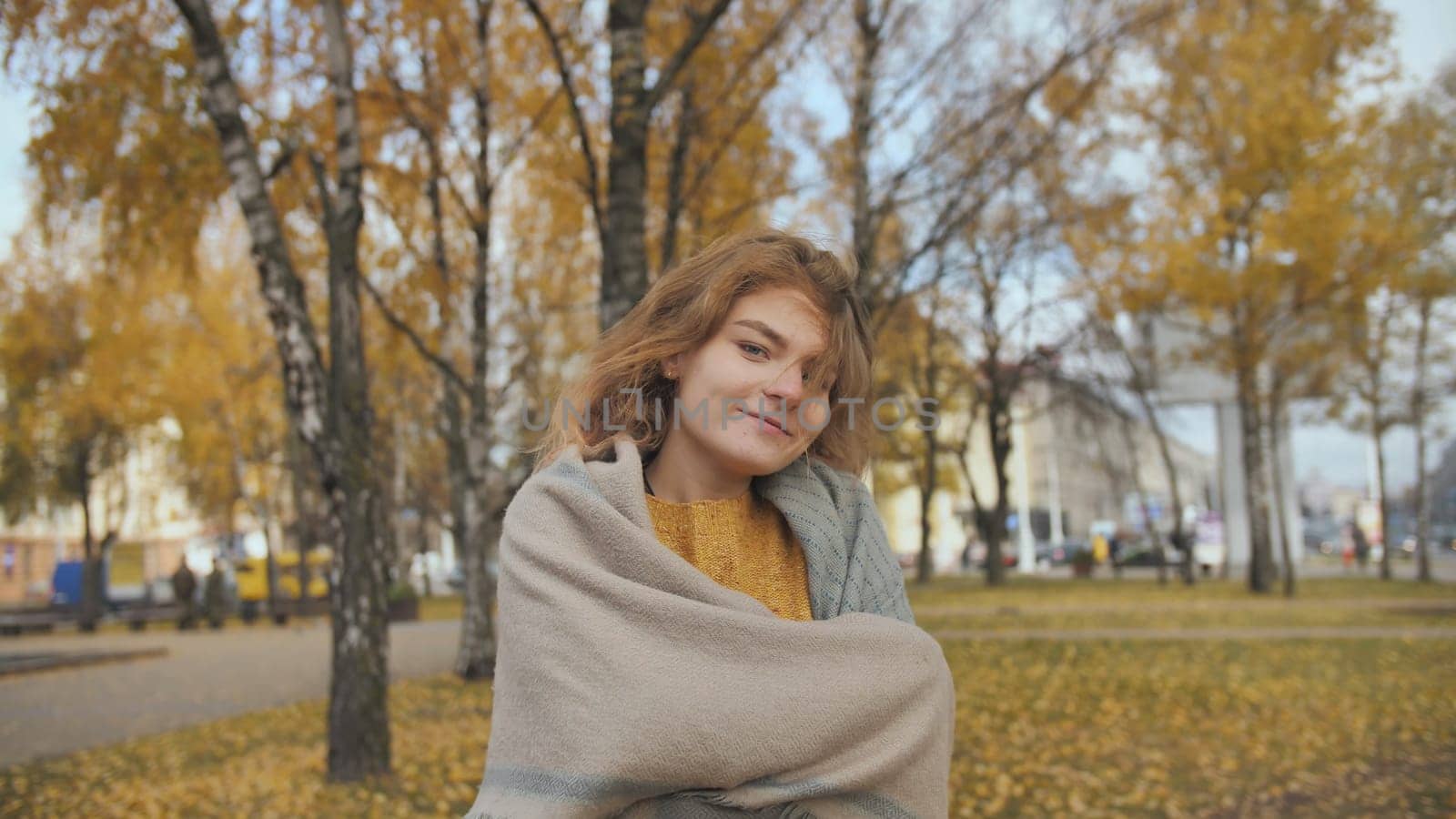 A red-haired, curly-haired girl twirls in the street in the fall