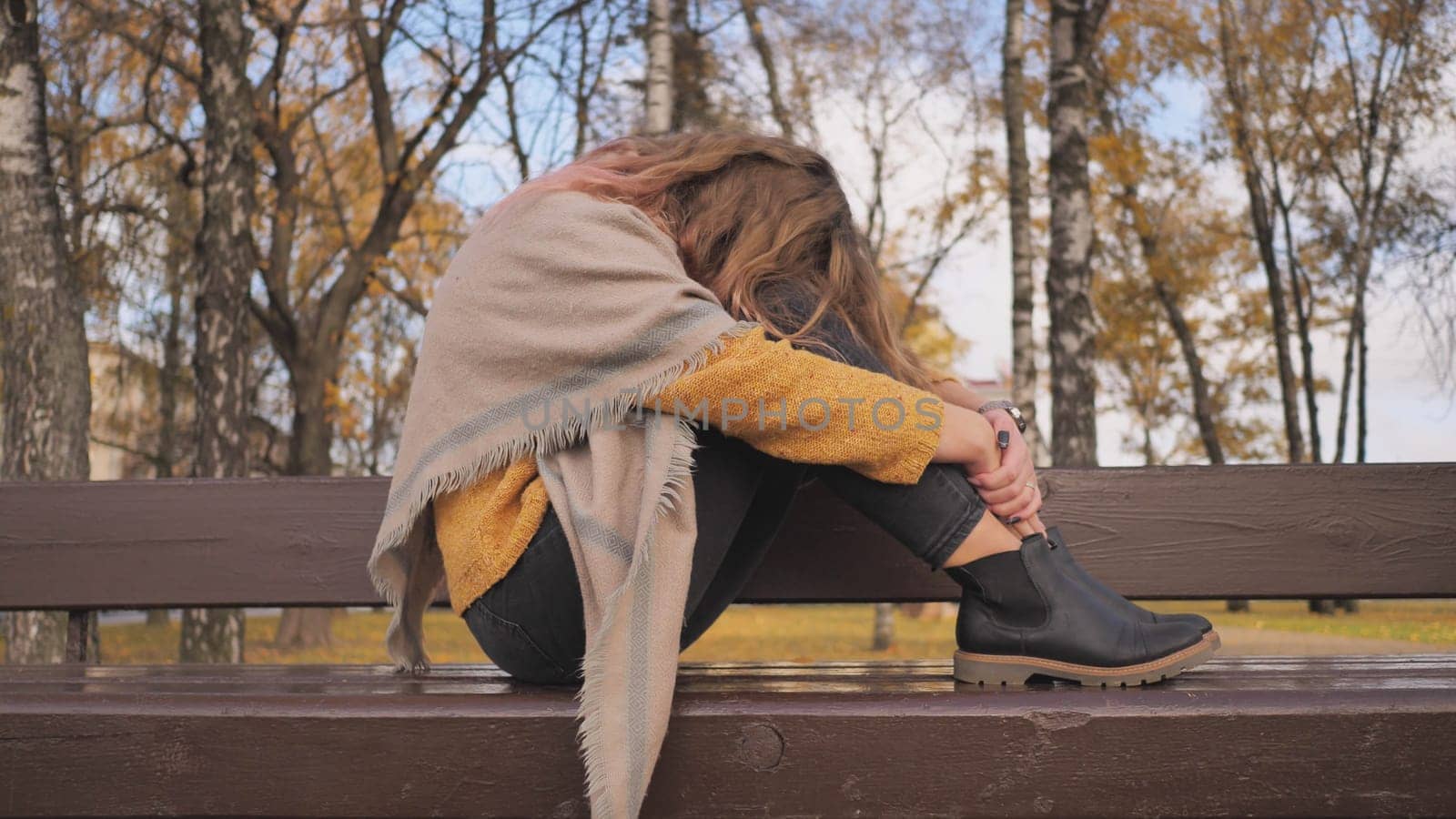 A young girl crying on a park bench in the fall. by DovidPro