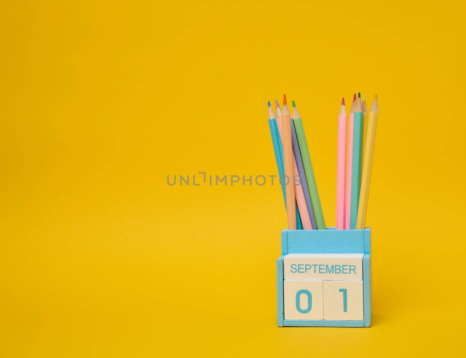 Multi-colored pencils and the date the first of September on the calendar. Yellow background