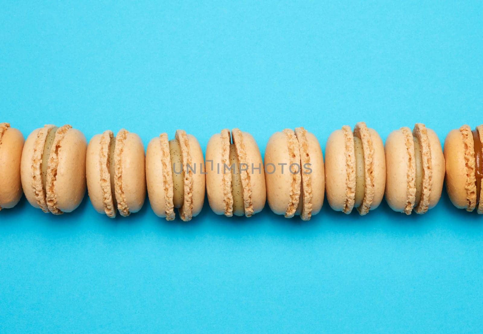 Chocolate macarons on a blue background, dessert. Top view