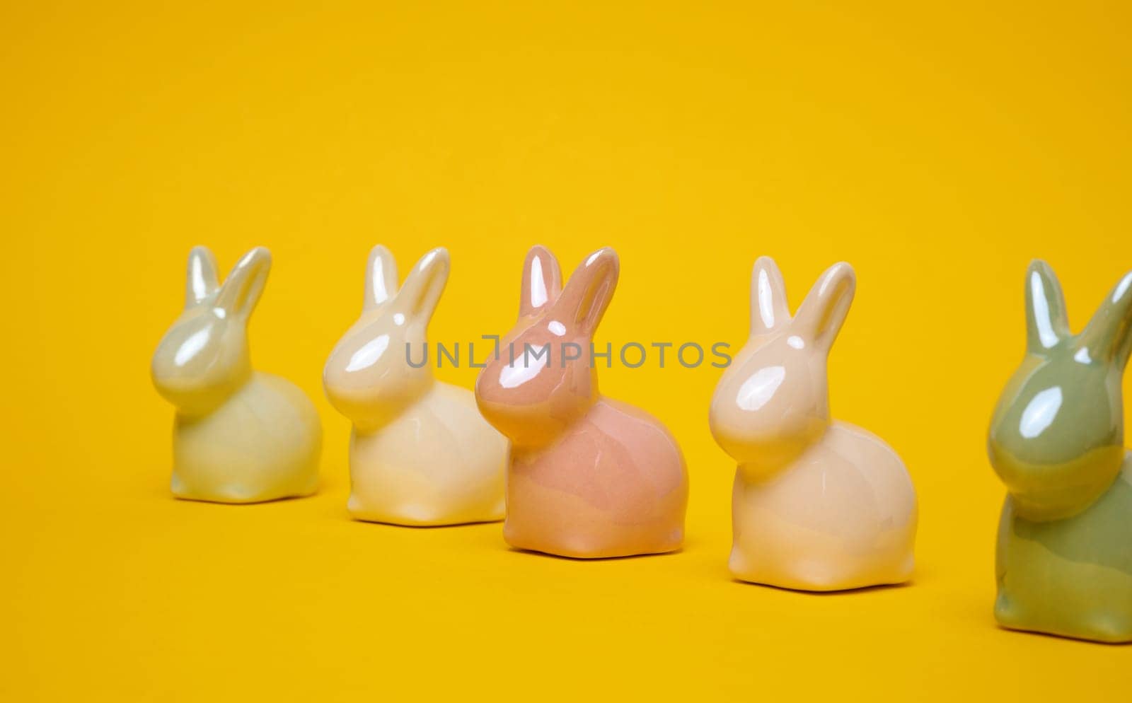 Ceramic decorative bunnies on a yellow background, festive Easter background by ndanko