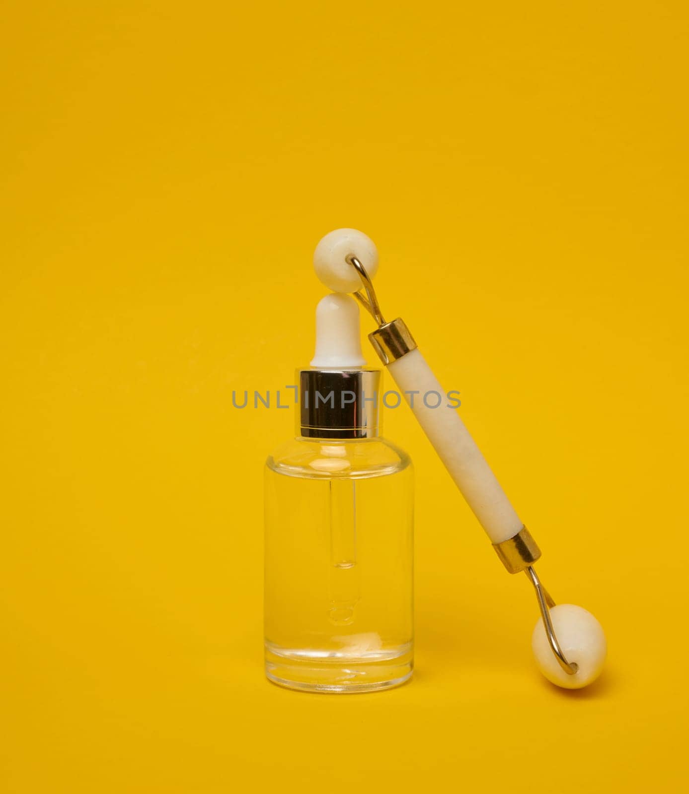 White transparent glass bottle with pipette and roller massager  by ndanko