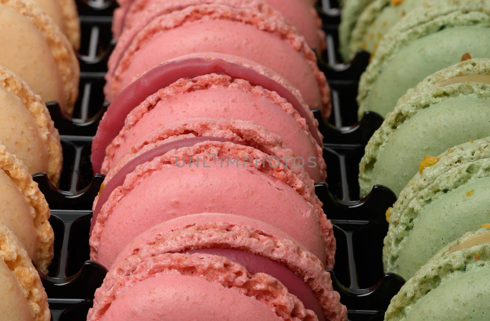 Raspberry and pistachio macarons in a plastic box, dessert. Close up