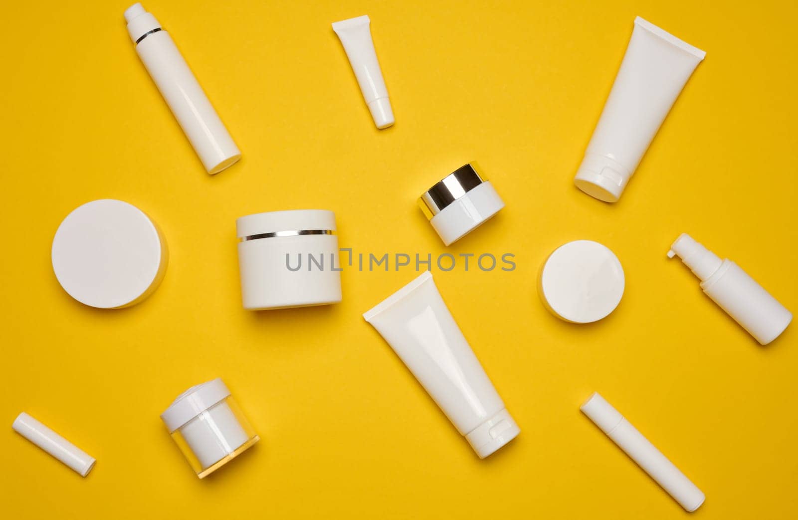 Various types of white plastic packaging, bottle, jar, tube on a yellow background. Container for cosmetics, top view