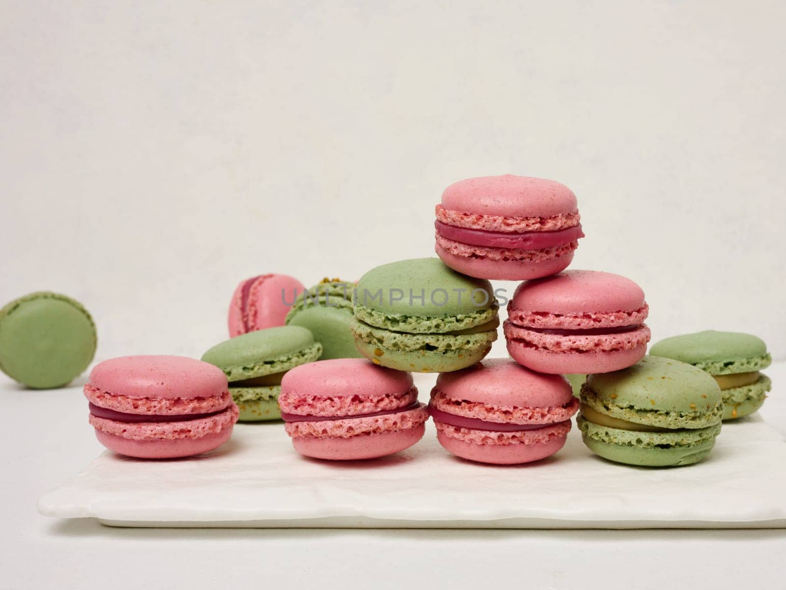 Raspberry and pistachio macarons on a white background, French dessert