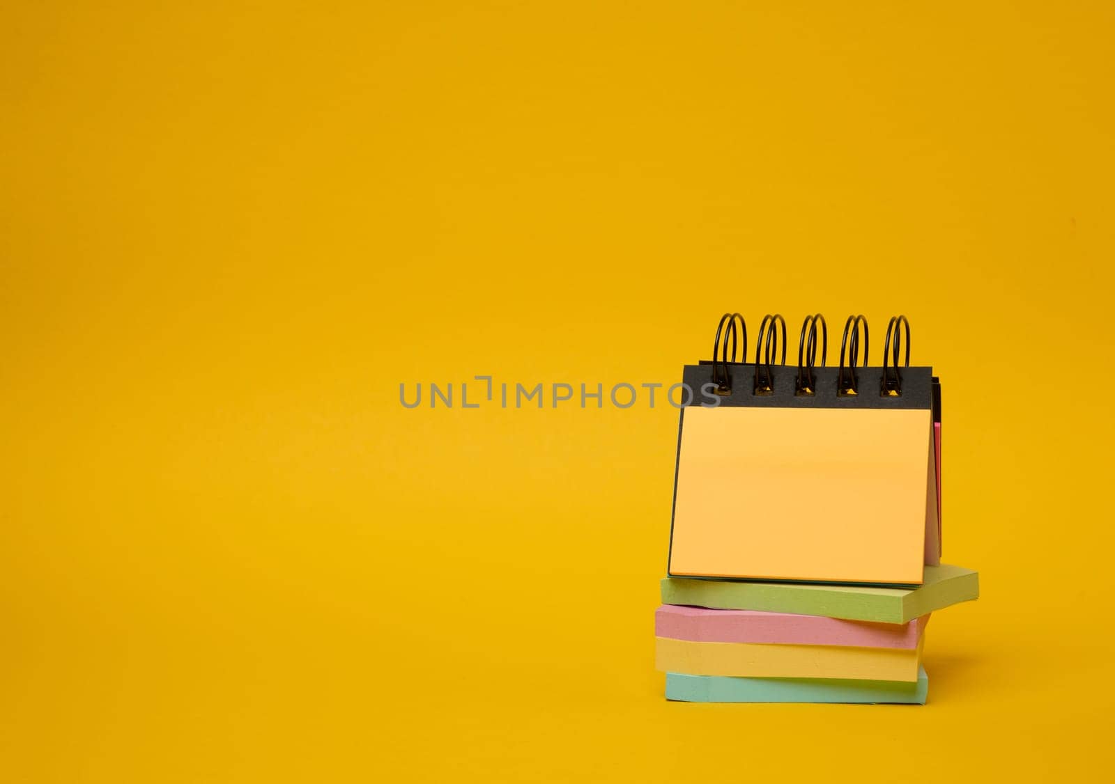 Stack of paper multi-colored stickers on a yellow background by ndanko