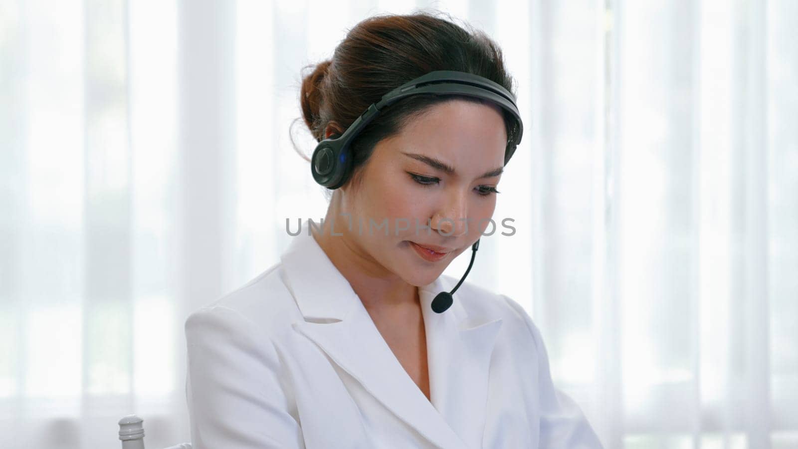 Businesswoman wearing headset working in office to support remote customer or colleague. Frustrated and tired call center customer support agent facing problem on providing vivancy service