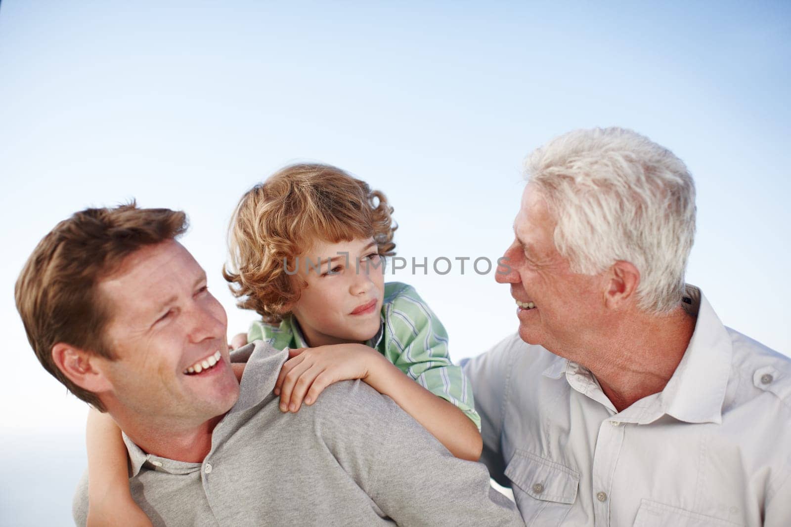 Grandfather, father and child by blue sky with smile for bonding, relationship and relax together. Family, generations and grandpa, dad and young boy on shoulders for holiday, vacation and weekend by YuriArcurs