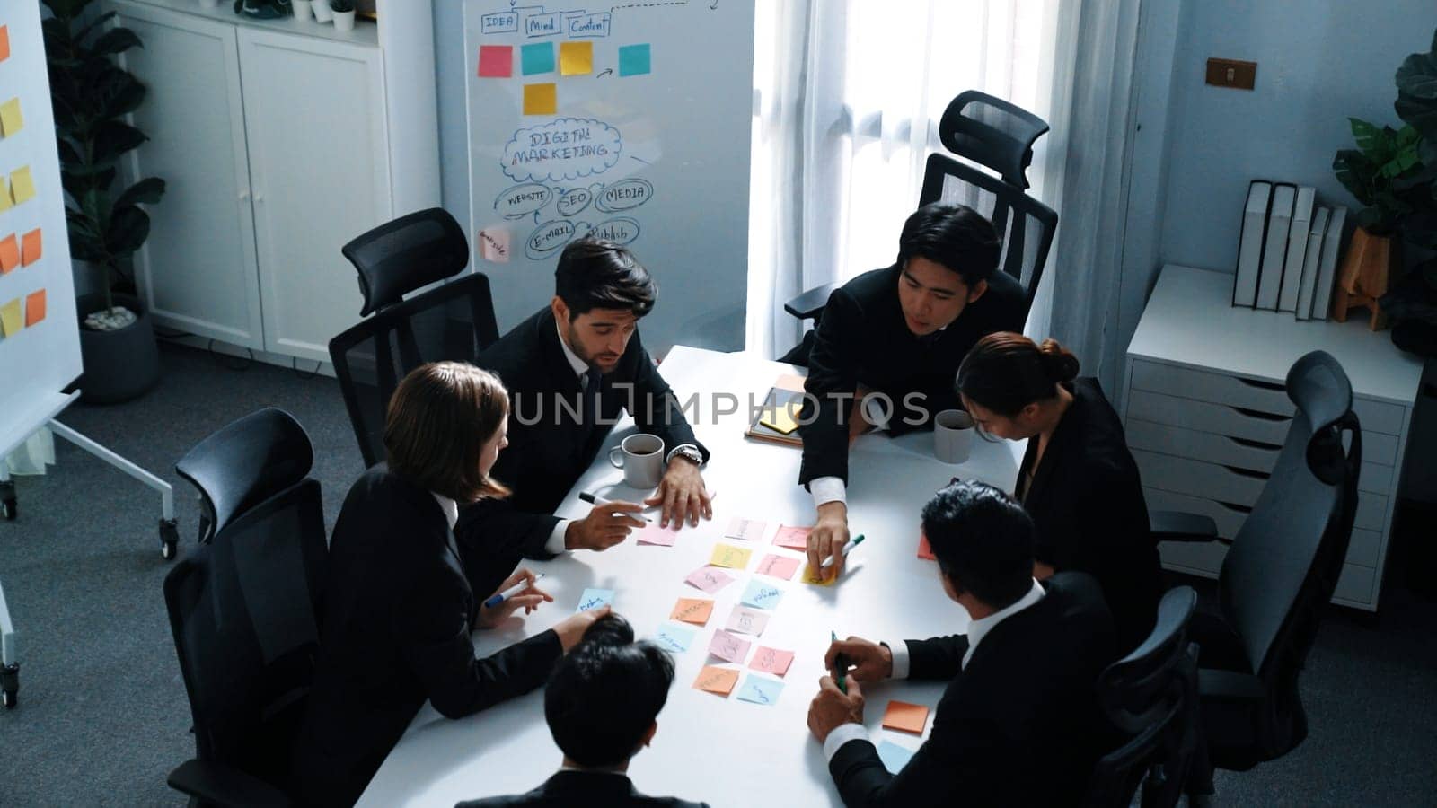 Top view of business people brainstorm idea by using sticky notes while planning marketing strategy at meeting room. Group of diverse team discuss about financial plan. Teamwork concept. Directorate.