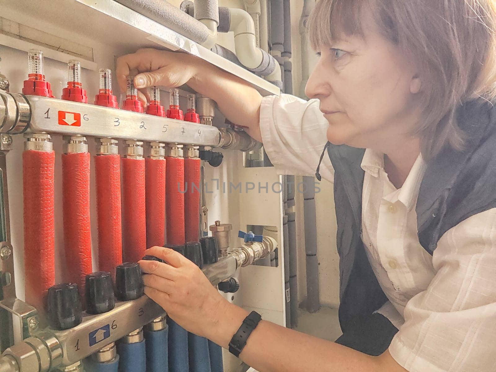 Female Technician Adjusting Industrial Water Filtration System. Middle aged Woman services a water filtration unit