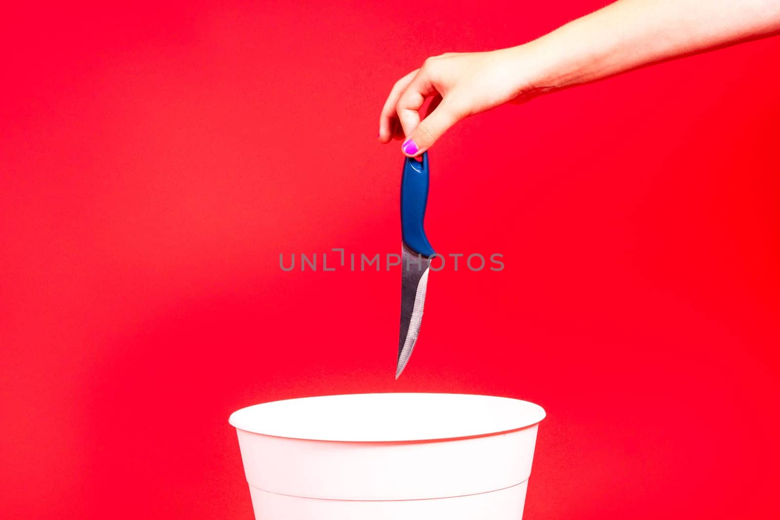 Knife is thrown into the trash basket. Red isolated background