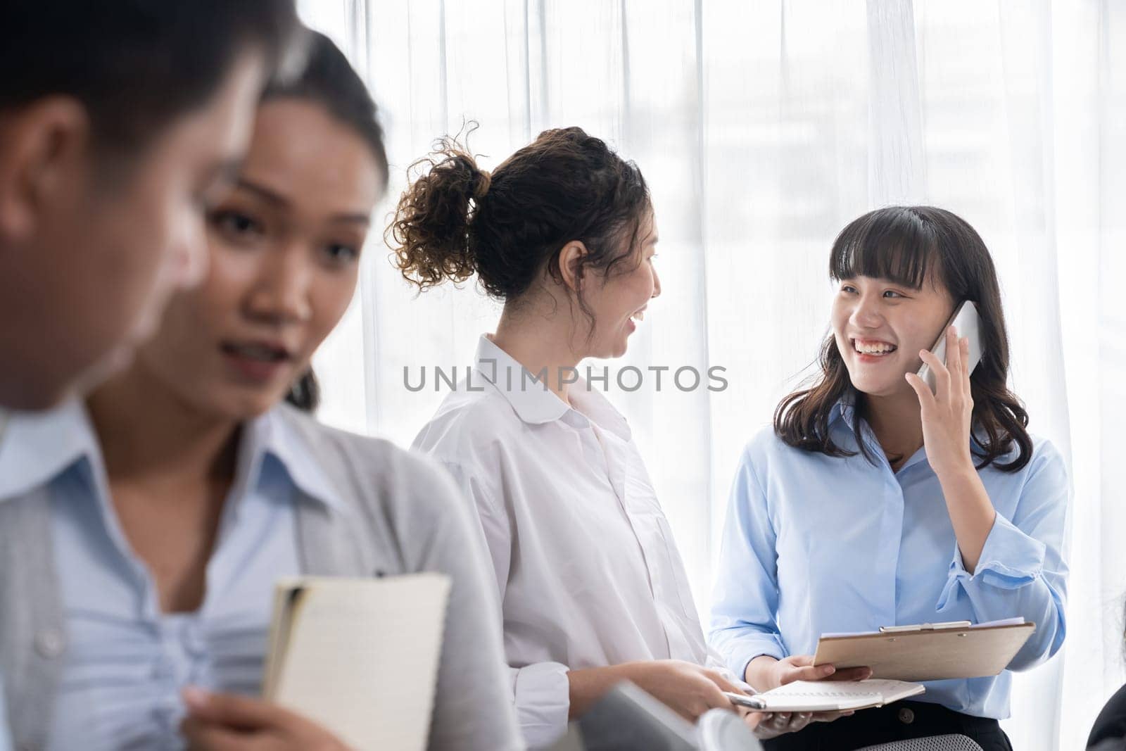 Asian office worker with smile working together in friendly corporate office environment. Group of happy business people in workplace with strong productive teamwork and sharing idea. Meticulous