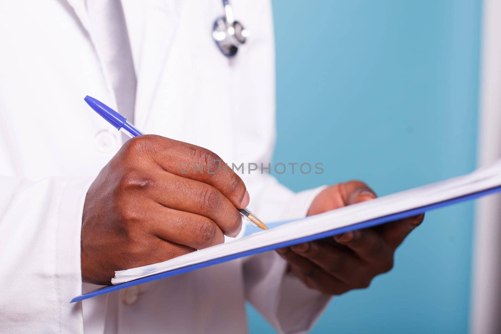 Close-up on African American pair of hands holding a pen and clipboard containing medical records. Detailed view of healthcare specialist reviewing patient charts and information.