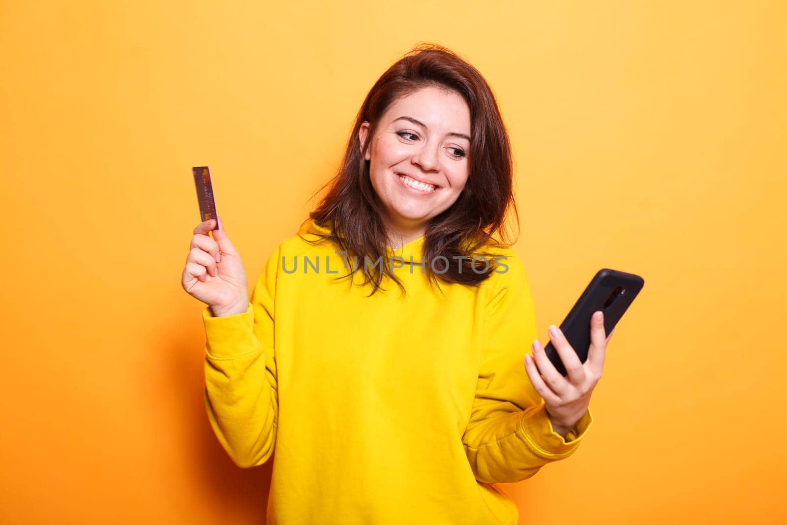 Caucasian woman using a smartphone to make an online purchase while holding her credit card. Positive woman paying for her purchases with a mobile device and internet banking.