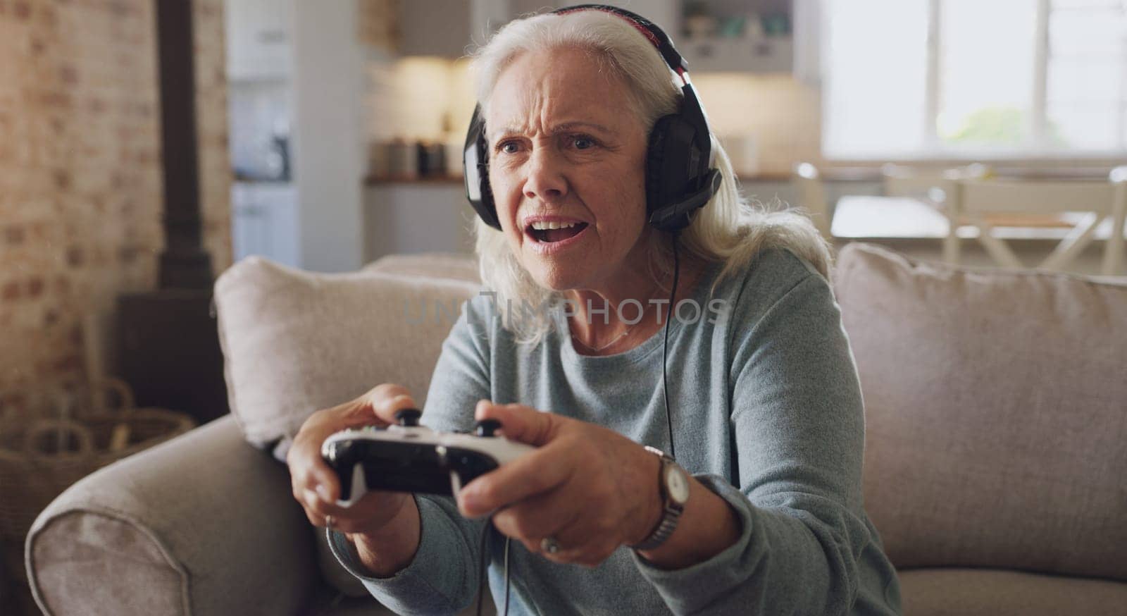 Headphones, senior woman and controller for video game, online streaming and relax for retirement at home. Tech, elderly person and frustrated with joystick for esports, gaming and challenge on sofa.