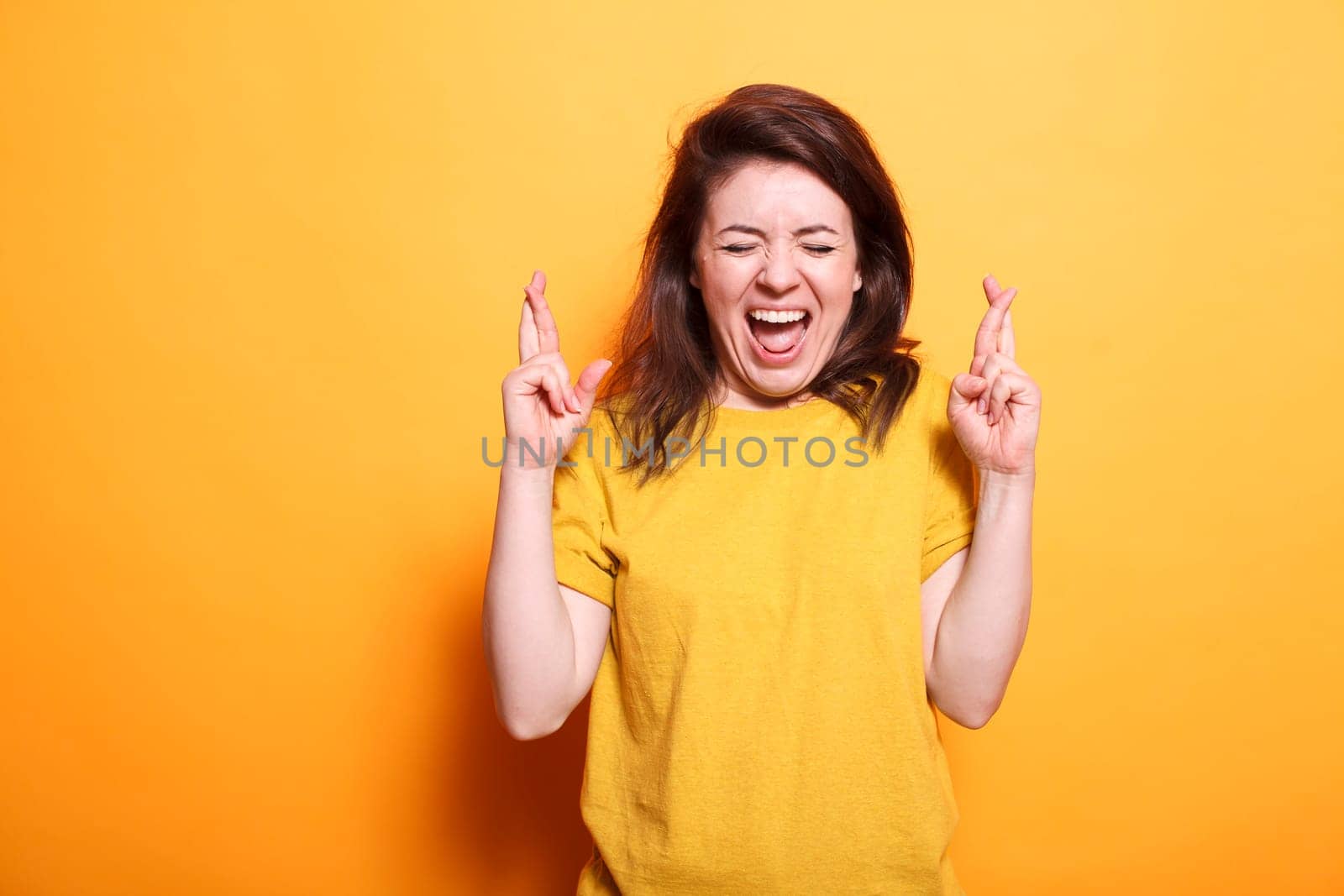 Excited woman having her fingers crossed by DCStudio