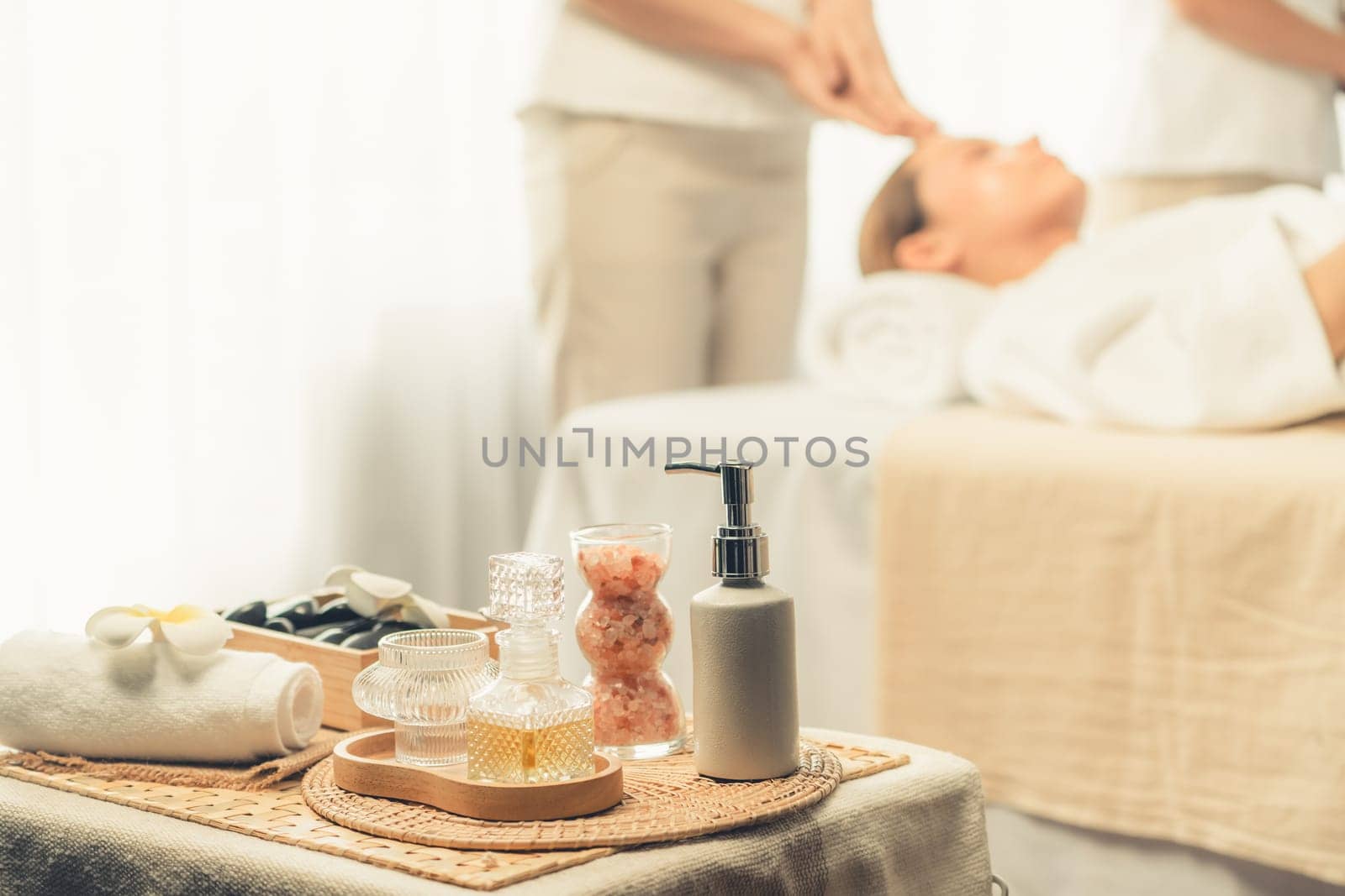 Aromatherapy massage on daylight ambiance or spa salon composition setup with focus decor and spa accessories on blur woman enjoying blissful aroma spa massage in resort or hotel background. Quiescent