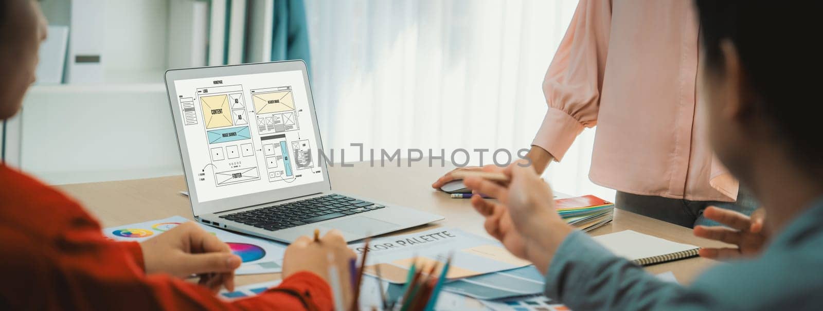 Cropped image of interior designer team discuss the material color while laptop displayed website wireframe designs for mobiles app and website. Creative design and business concept. Variegated.