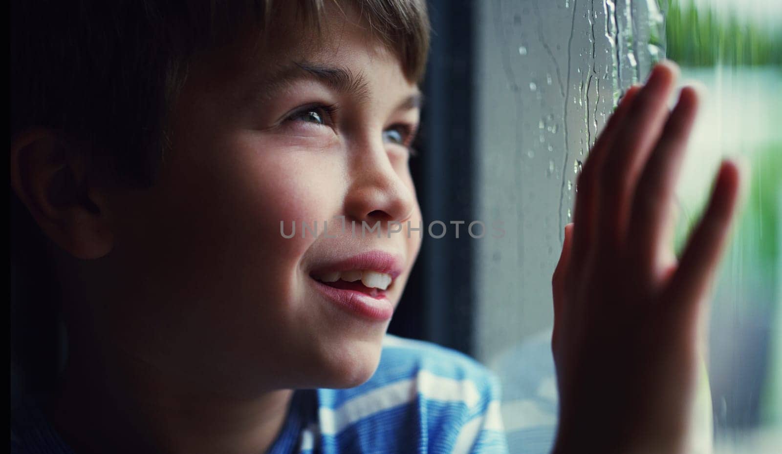 Child, window and smile at rain drops or thinking in home with cold weather, thoughts or future. Male person, boy and hand or contemplating in winter for decision or wondering, youth or daydreaming.