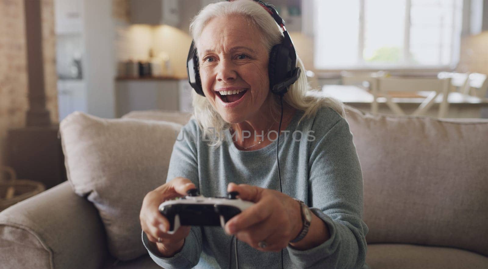 Headphones, senior woman and joystick for video game, online streaming and relax for retirement at home. Technology, elderly person and happiness with smile from esports, gaming and challenge on sofa.