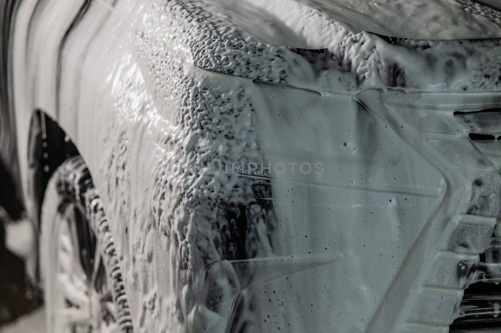 Foam drips from the bumper of a black car. Car wash. by mrwed54