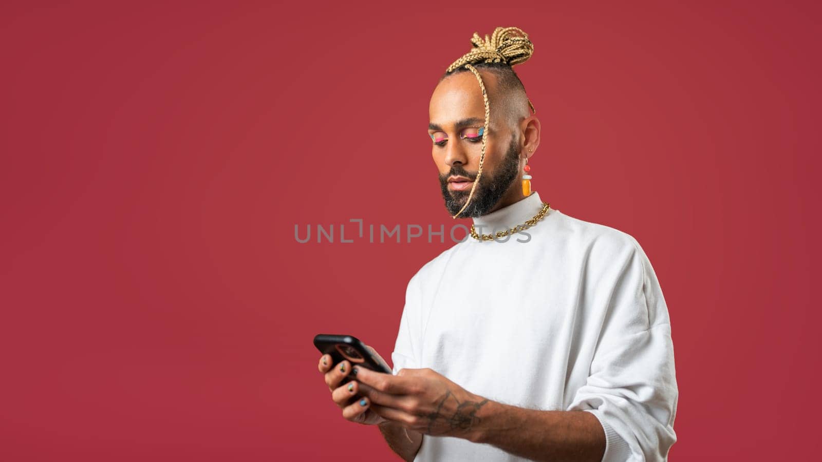 Trendy black latin gay man in white clothes use smartphone on red background studio portrait People lifestyle fashion lgbtq concept