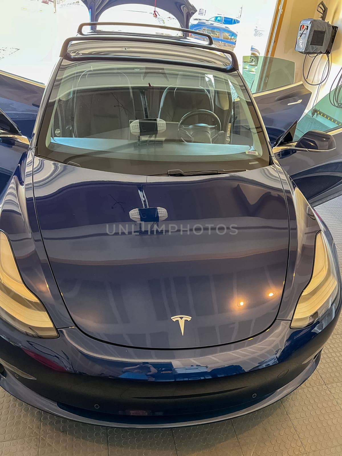 Castle Rock, Colorado, USA-March 14, 2024-A shiny blue Tesla Model 3 sits in the well-kept garage of a single-family house, its sleek design accentuated by the gentle care of a home car wash.