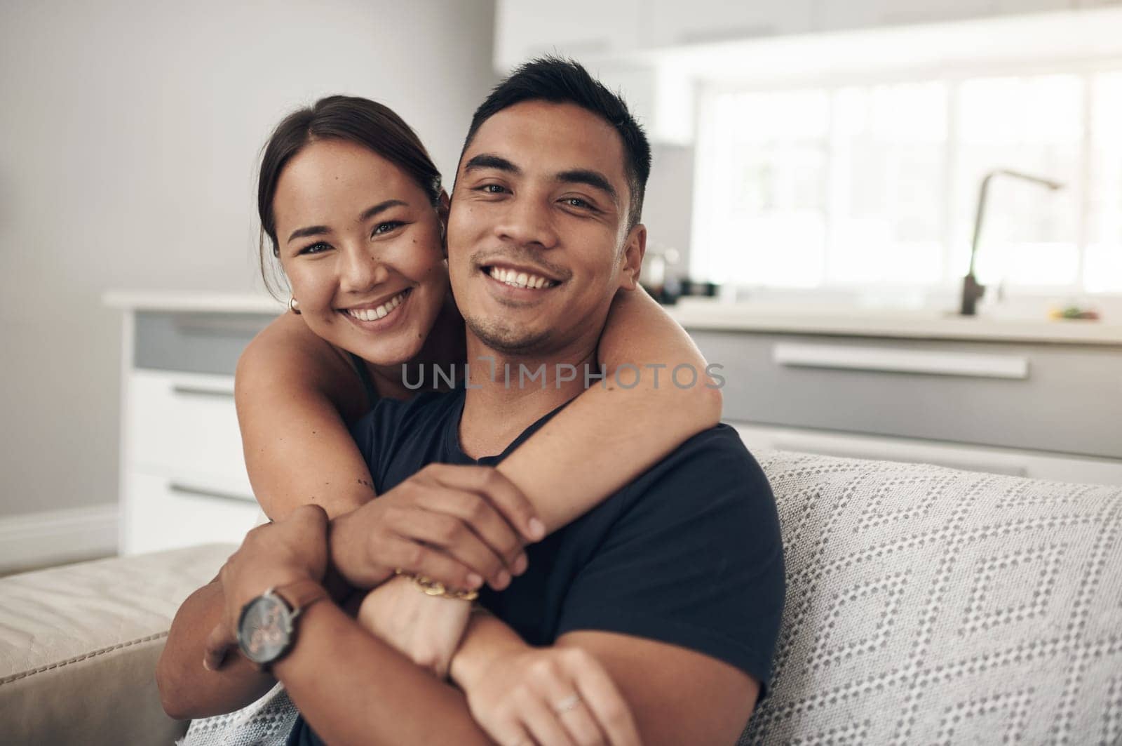 Portrait, home and hug with couple, relax and happiness with love or bonding together in lounge. Face, apartment or man with woman or embrace with romance or relationship with marriage, care or trust by YuriArcurs