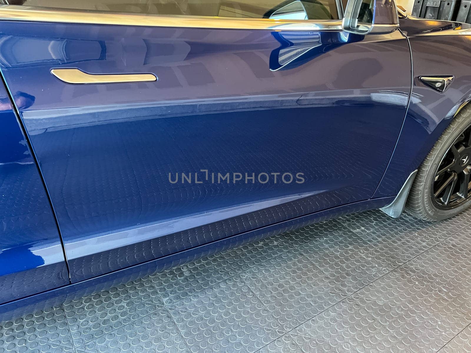 Castle Rock, Colorado, USA-March 14, 2024-A shiny blue Tesla Model 3 sits in the well-kept garage of a single-family house, its sleek design accentuated by the gentle care of a home car wash.