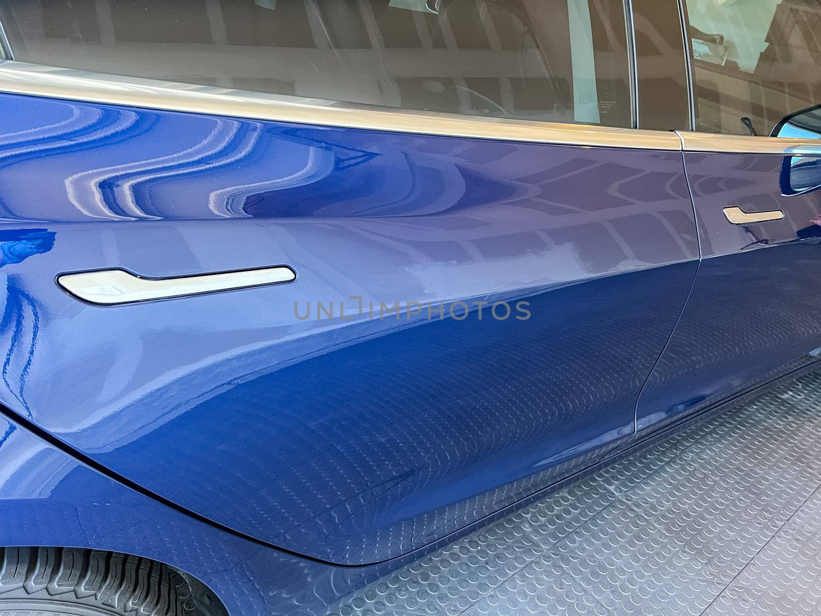 Castle Rock, Colorado, USA-March 14, 2024-A shiny blue Tesla Model 3 sits in the well-kept garage of a single-family house, its sleek design accentuated by the gentle care of a home car wash.