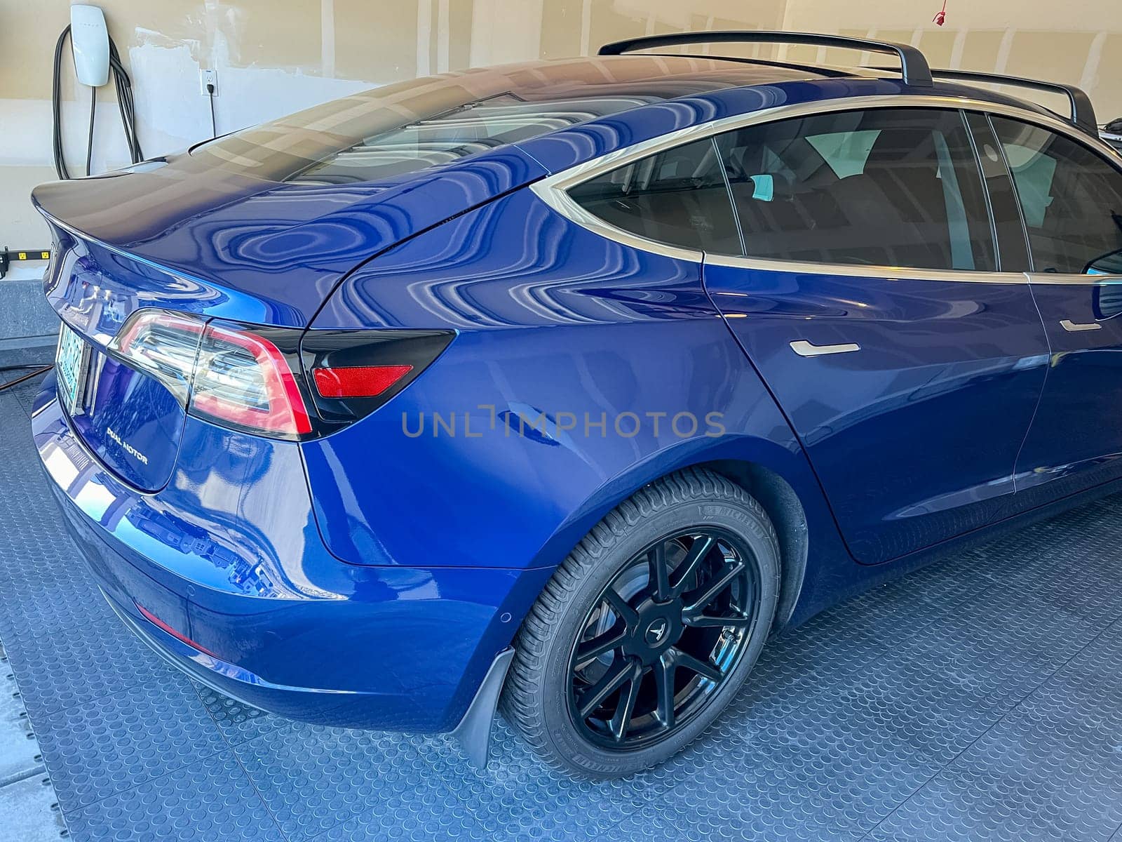 Castle Rock, Colorado, USA-March 14, 2024-A shiny blue Tesla Model 3 sits in the well-kept garage of a single-family house, its sleek design accentuated by the gentle care of a home car wash.
