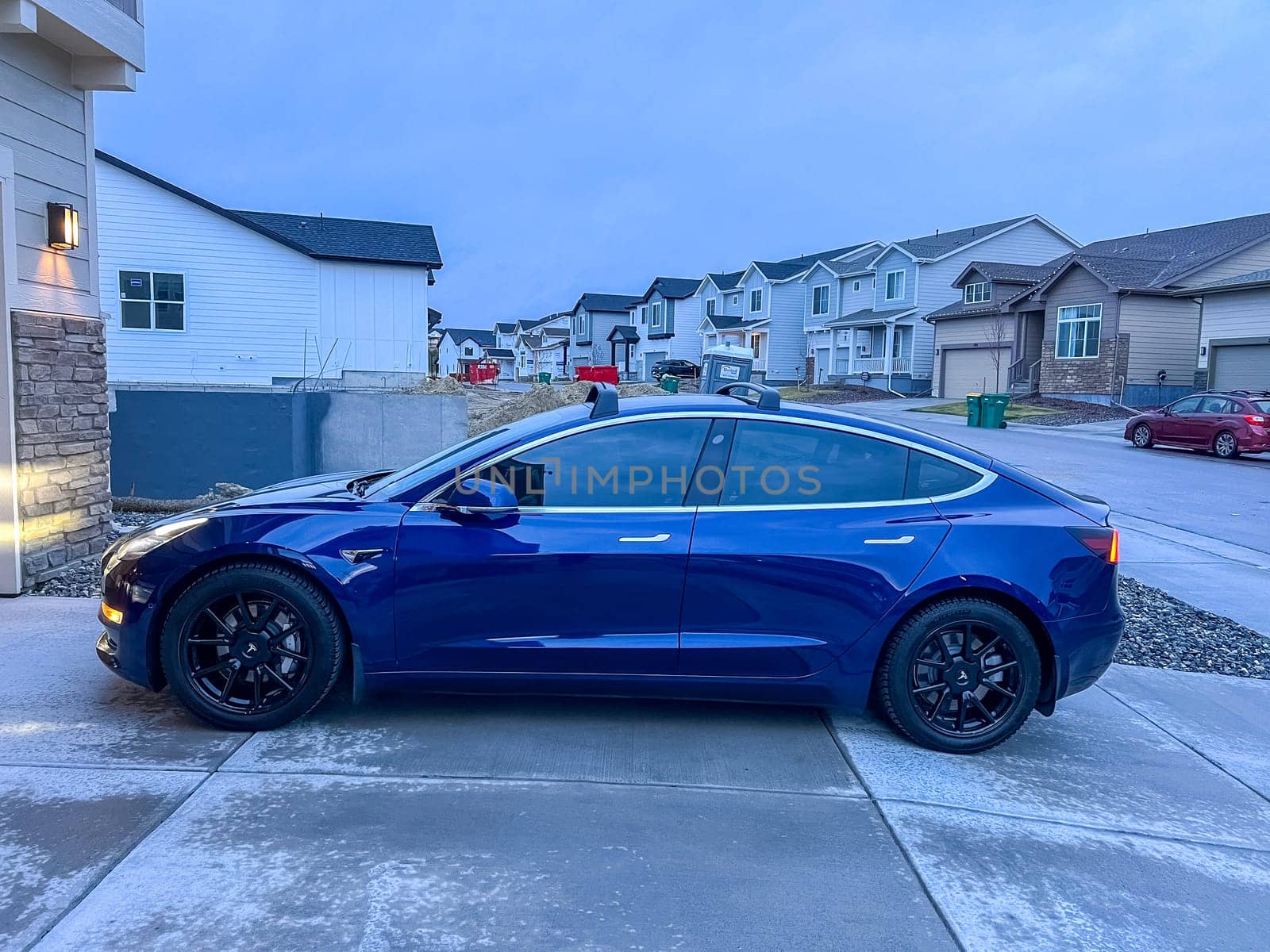 Castle Rock, Colorado, USA-March 14, 2024-A shiny blue Tesla Model 3 sits in the well-kept garage of a single-family house, its sleek design accentuated by the gentle care of a home car wash.