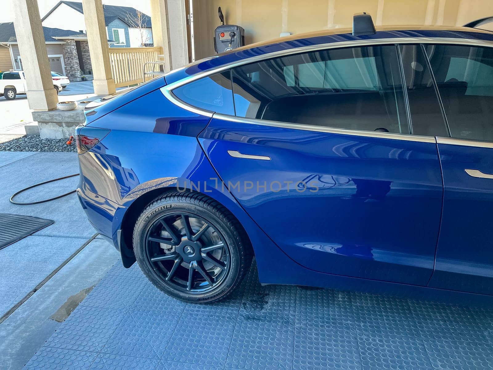 Castle Rock, Colorado, USA-March 14, 2024-A shiny blue Tesla Model 3 sits in the well-kept garage of a single-family house, its sleek design accentuated by the gentle care of a home car wash.