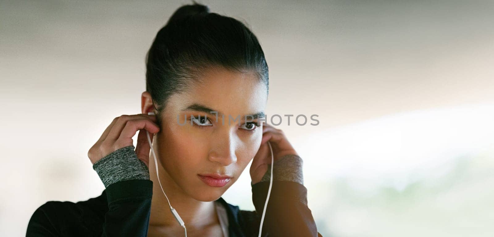 Fitness, focus and woman with earphones for streaming music, listening to podcast or radio station. Serious, sport and female athlete for running, morning workout or cardio exercise on banner.