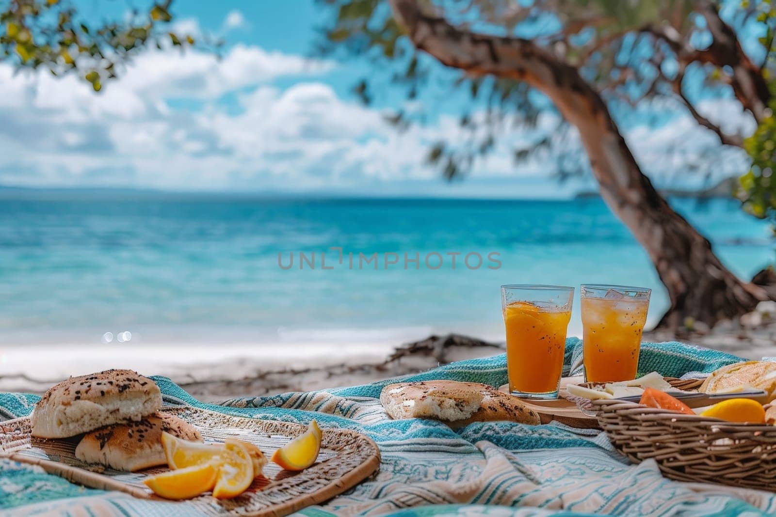 A picnic scene with food and glass of orange juice drink on picnic blanket at beach.