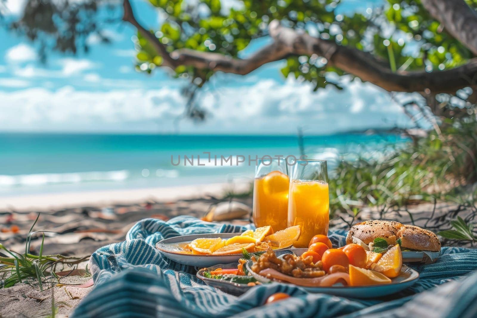 A picnic scene with food and glass of orange juice drink on picnic blanket at beach.