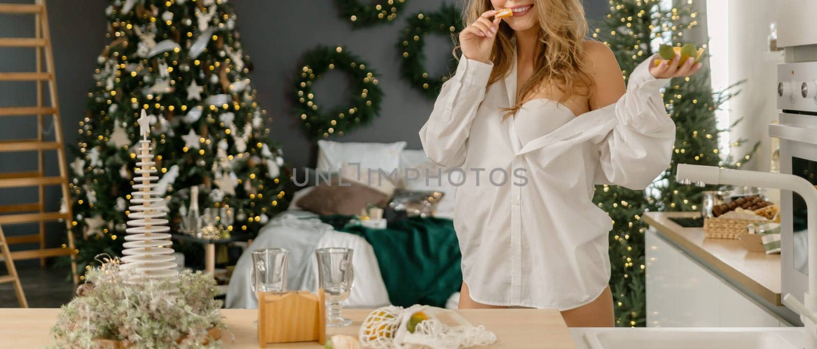 Woman Kitchen Christmas decor in white shirt, peeling tangerines. Illustrating New Year's mood holiday preparations.