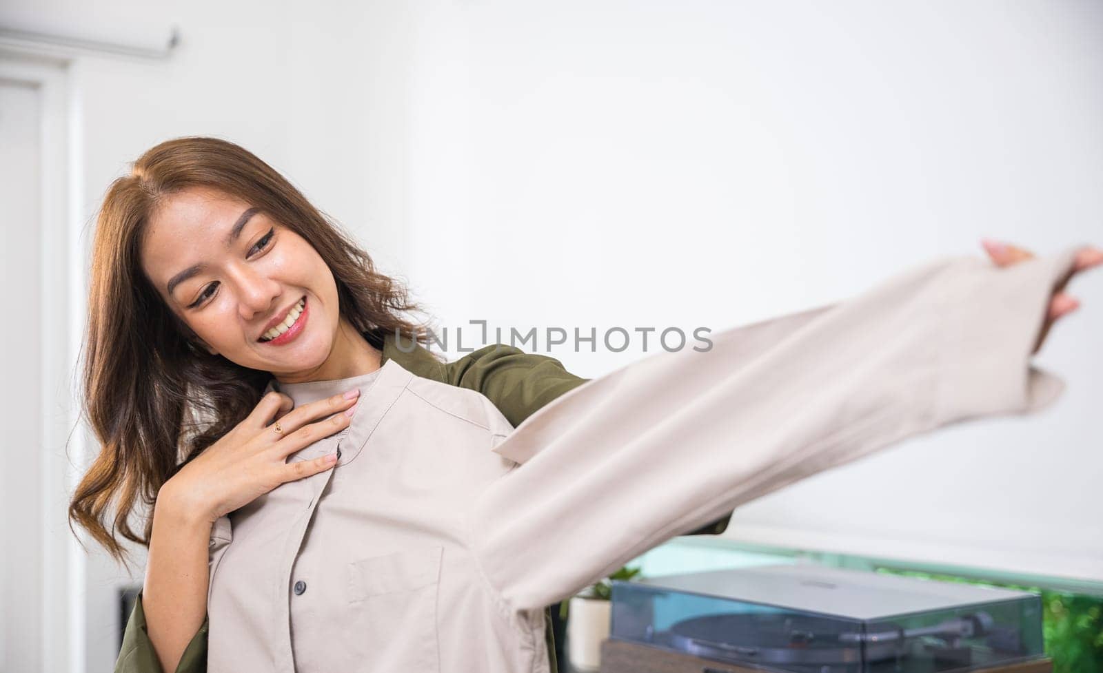 The woman in the image is smiling and appears to be admiring a piece of clothing. She looks happy and satisfied, perhaps pleased with a new purchase or the quality of the garment