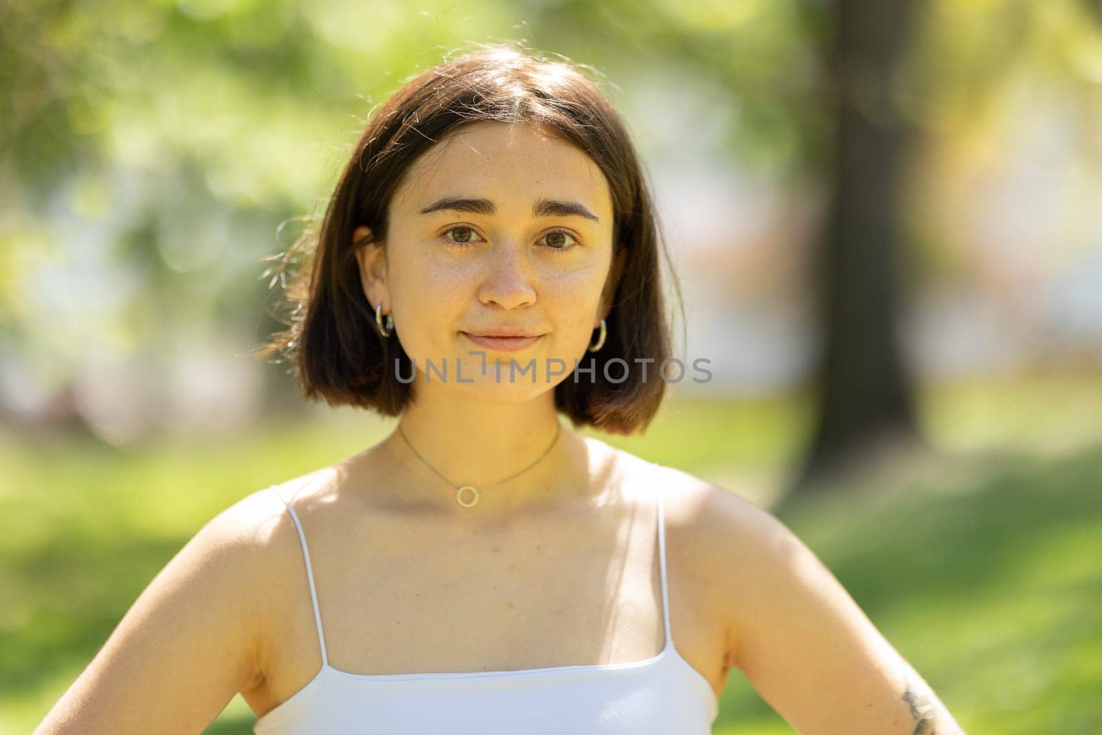 A woman with short hair and a white tank top is smiling for the camera by Studia72