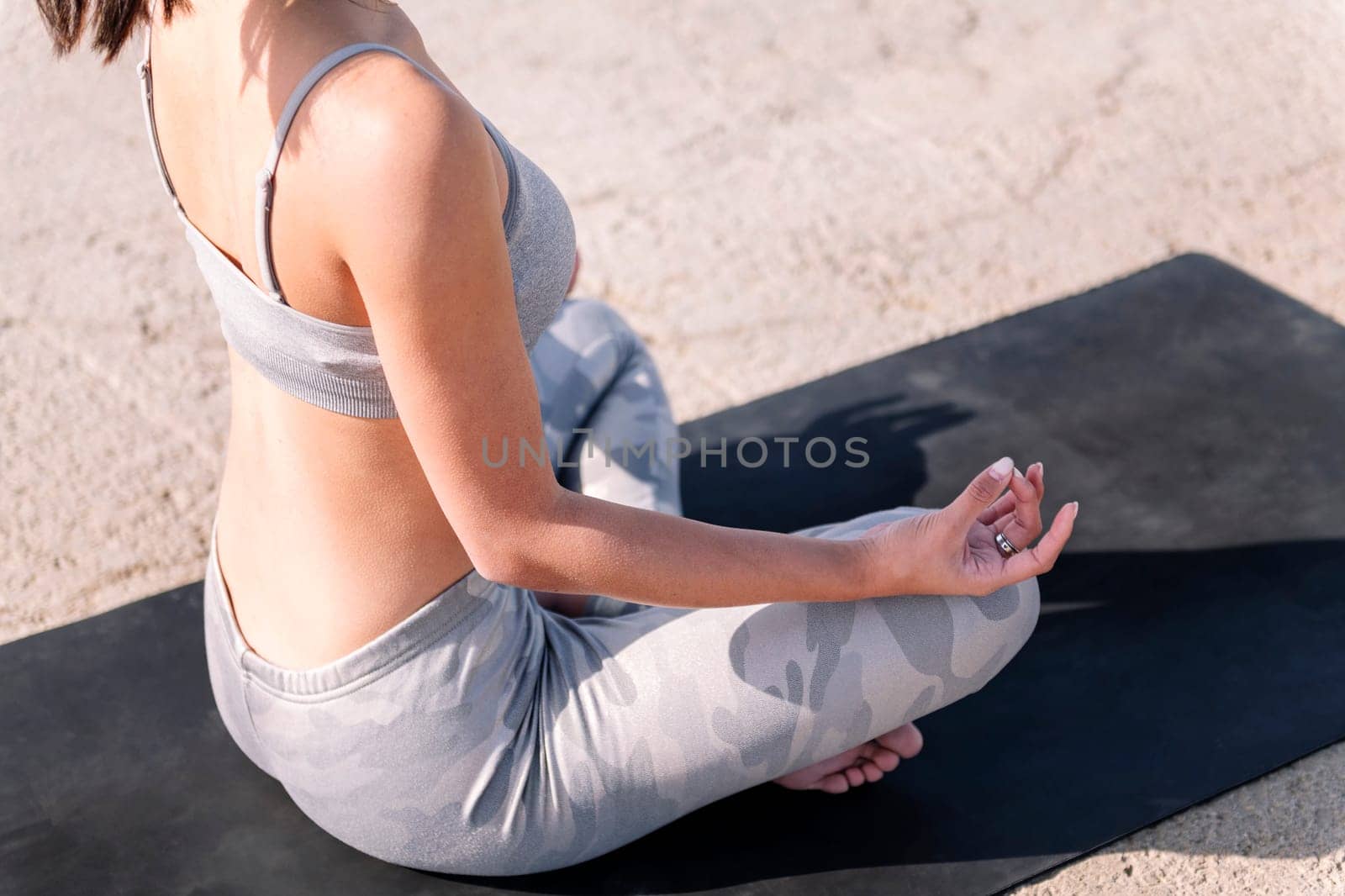 unrecognizable woman doing meditation sitting with legs crossed on a yoga mat, concept of mental relaxation and healthy lifestyle