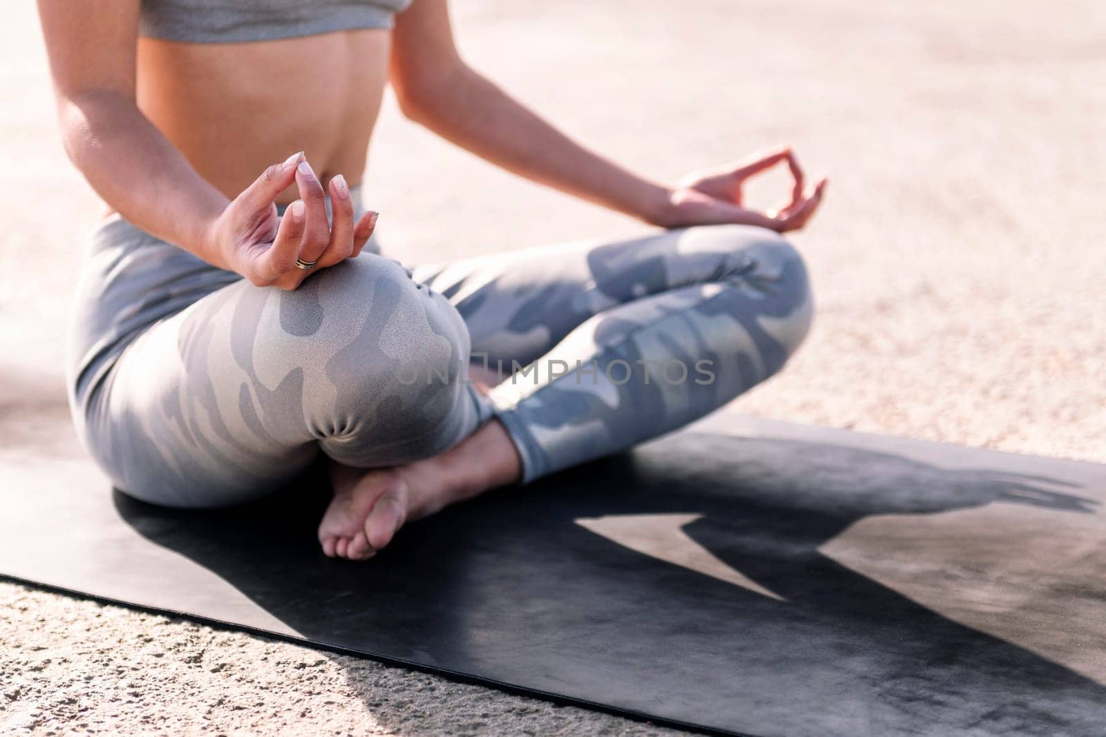 detail of the crossed legs of a woman doing meditation sitting on a yoga mat, concept of mental relaxation and healthy lifestyle